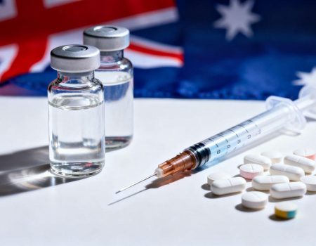 Unmarked vials, syringes, pills, Australian flag background
